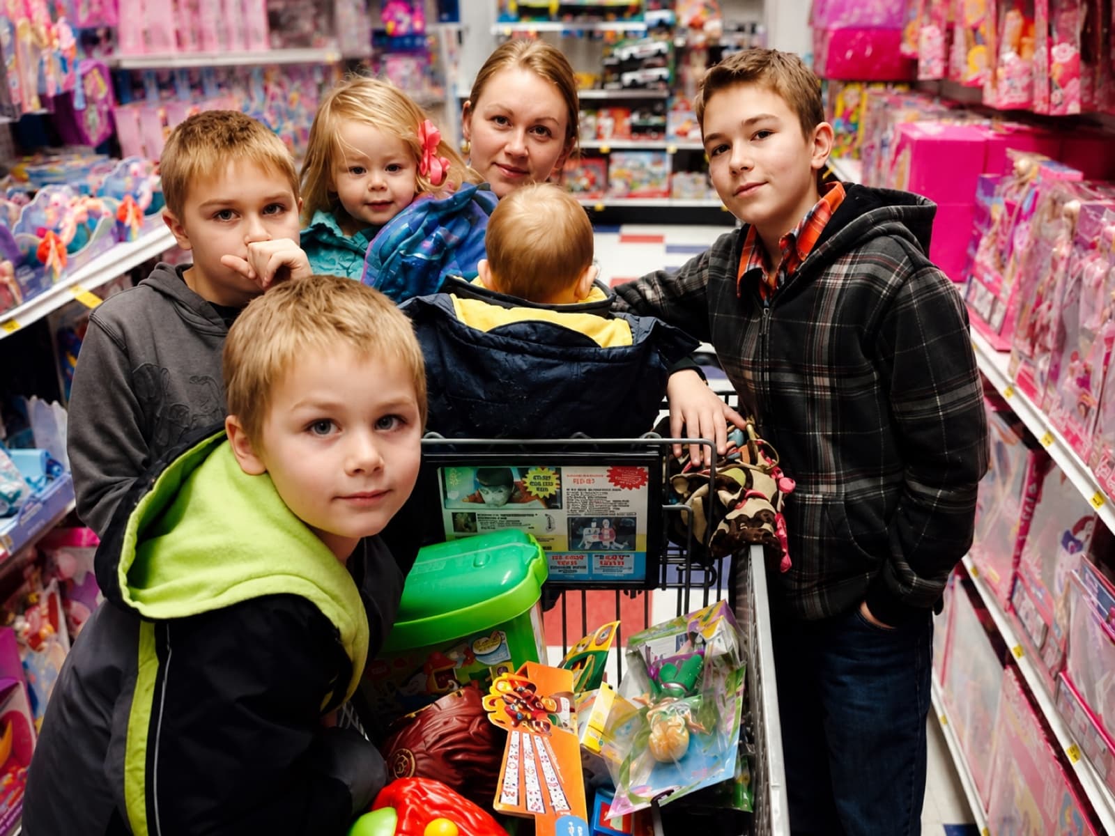 Crystal Stapley and four of our kids in a toy-store aisle, shopping cart full of toys, surrounded by shelves of pink doll boxes.